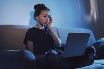 Przestraszona dziewczynka patrzy w ekran laptopa