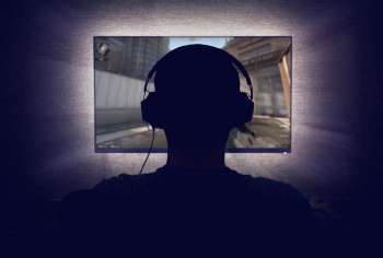 Gracz przed monitorem na ciemnym tle